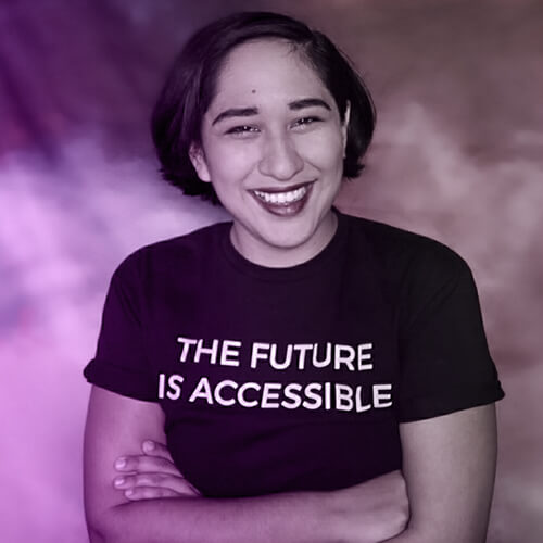 Annie Segarra smiling widely at the camera while wearing a shirt reading "The Future Is Accessible"