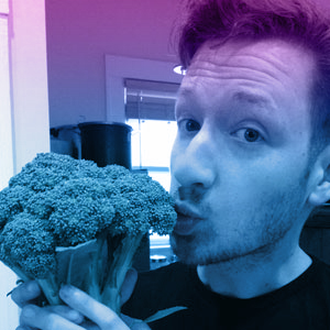 Indoor photo of Nick O'Neill holding and kissing a sten of broccoli